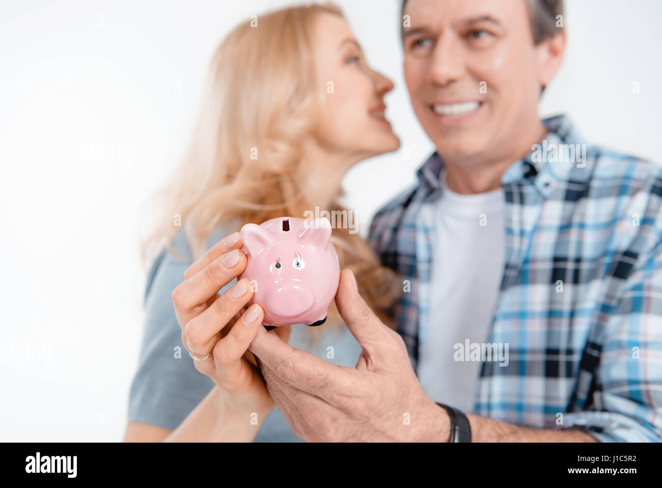 Front view of happy couple holding piggy bank on white Stock Photo - Alamy