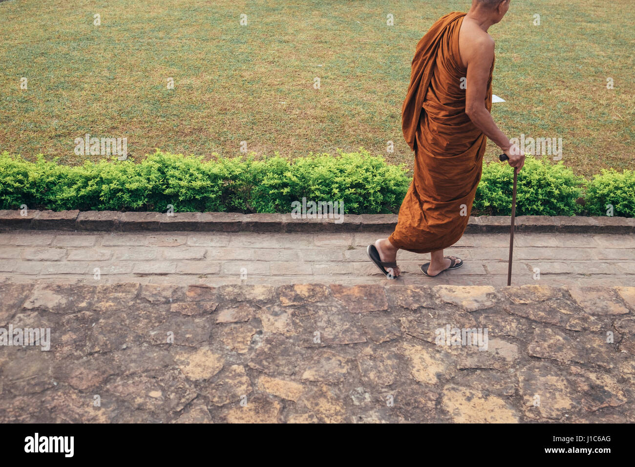 Monk walking with cane Stock Photo