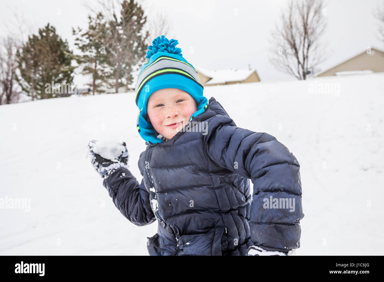 Smiling boy throwing snowball in winter Stock Photo