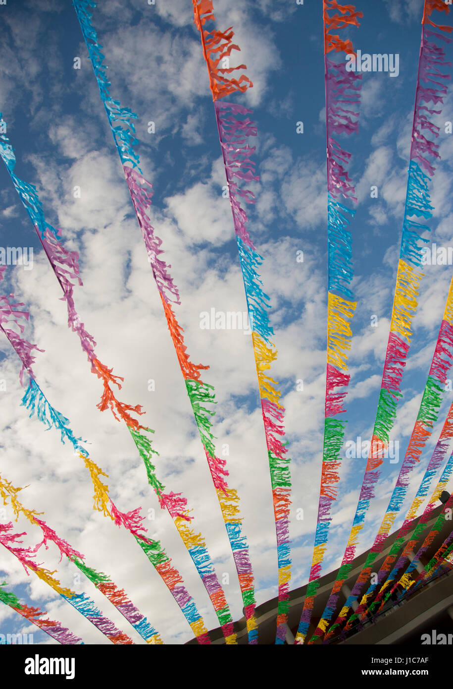 Multicolor flags blowing in wind under blue sky Stock Photo