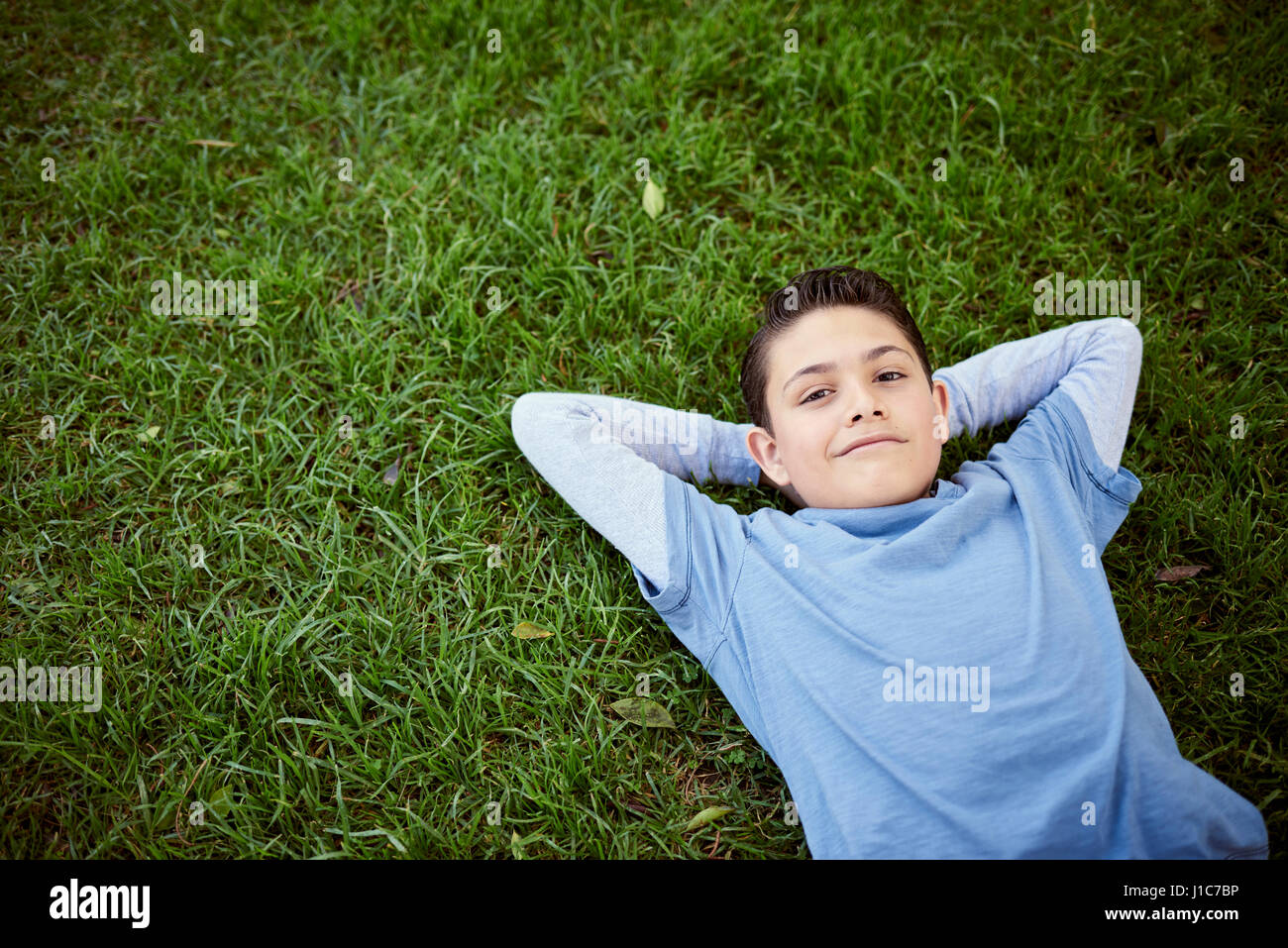 Smiling Hispanic boy laying in grass Stock Photo