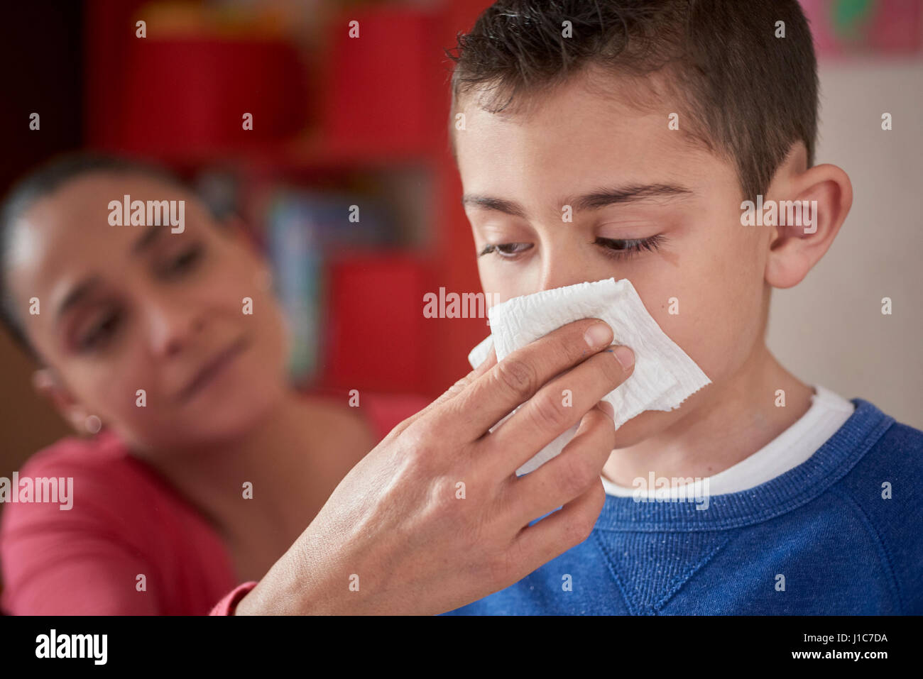 Hispanic mother wiping nose of son with tissue Stock Photo