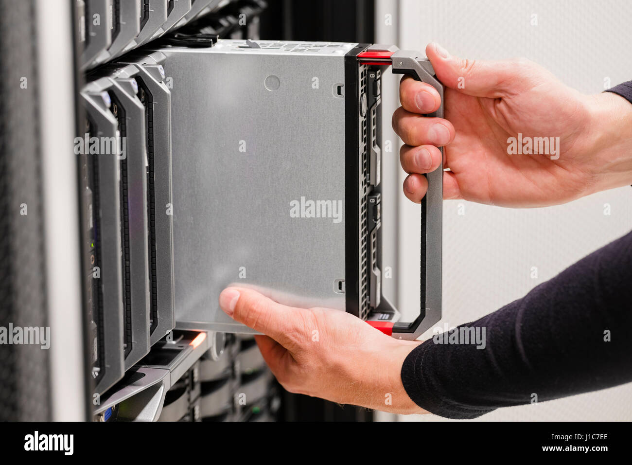 IT professional installs server cluster in large datacenter Stock Photo