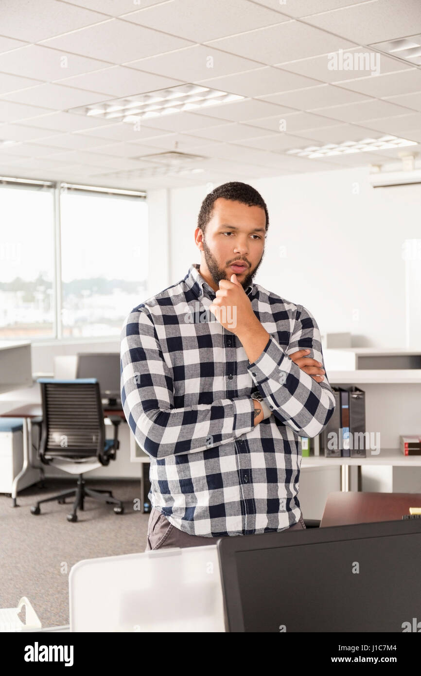 Pensive Mixed Race man standing in office Stock Photo