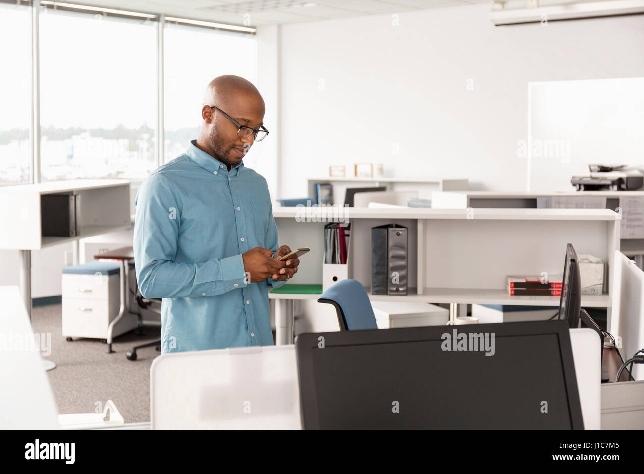 African American man texting on cell phone in office Stock Photo
