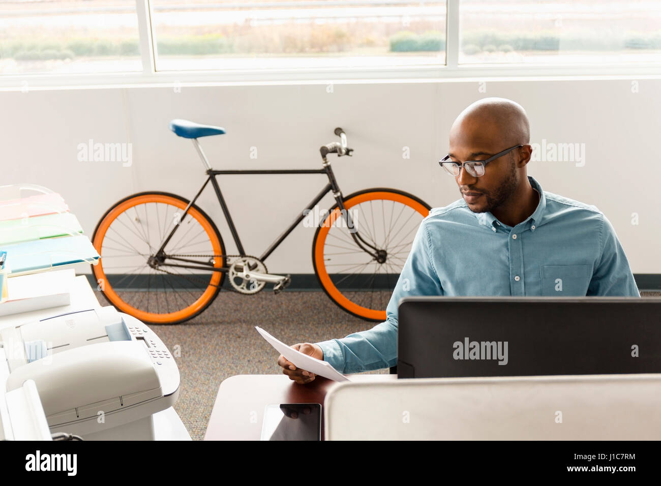 African American man reading paperwork in office Stock Photo
