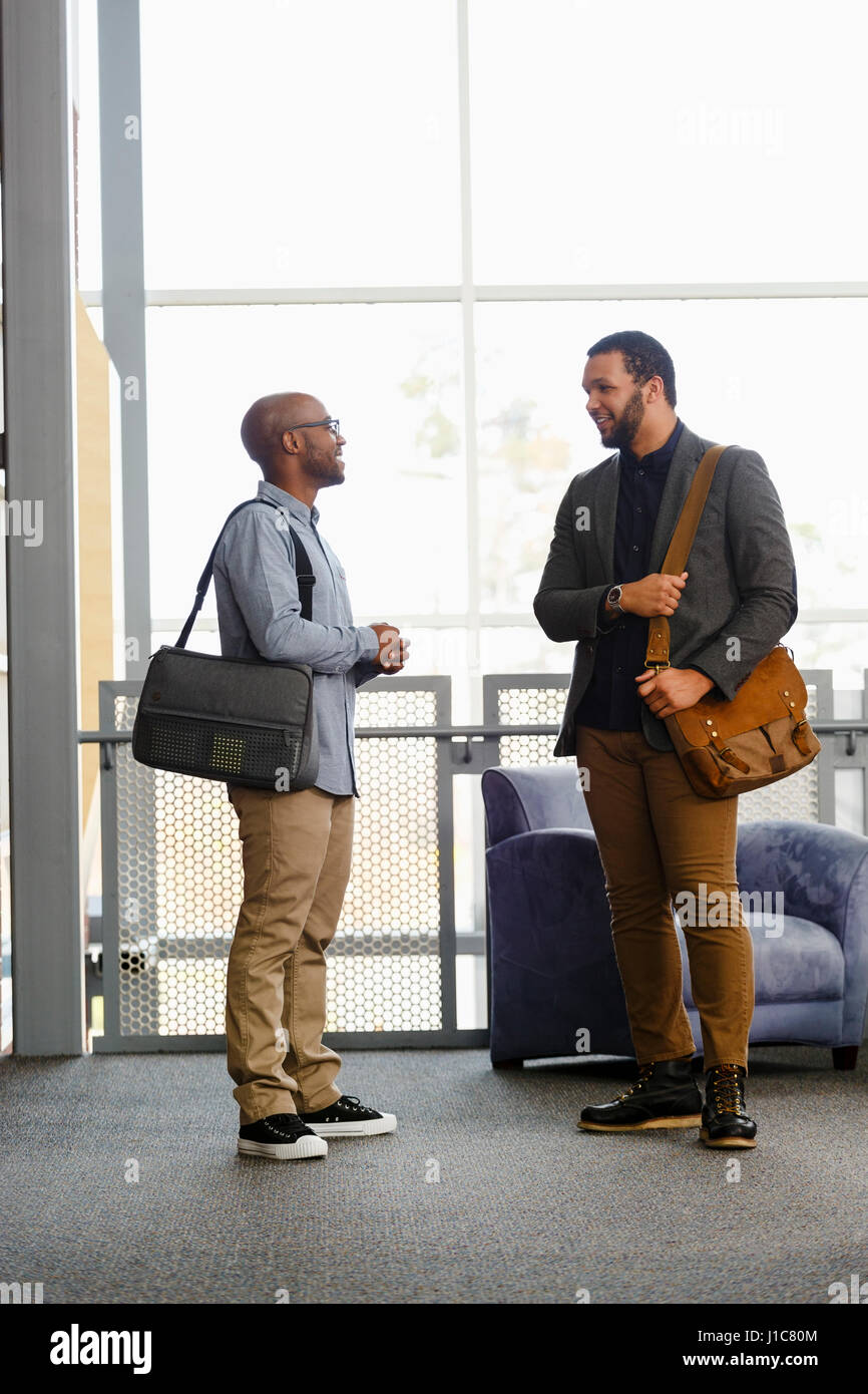 Men carrying briefcases talking in lobby Stock Photo