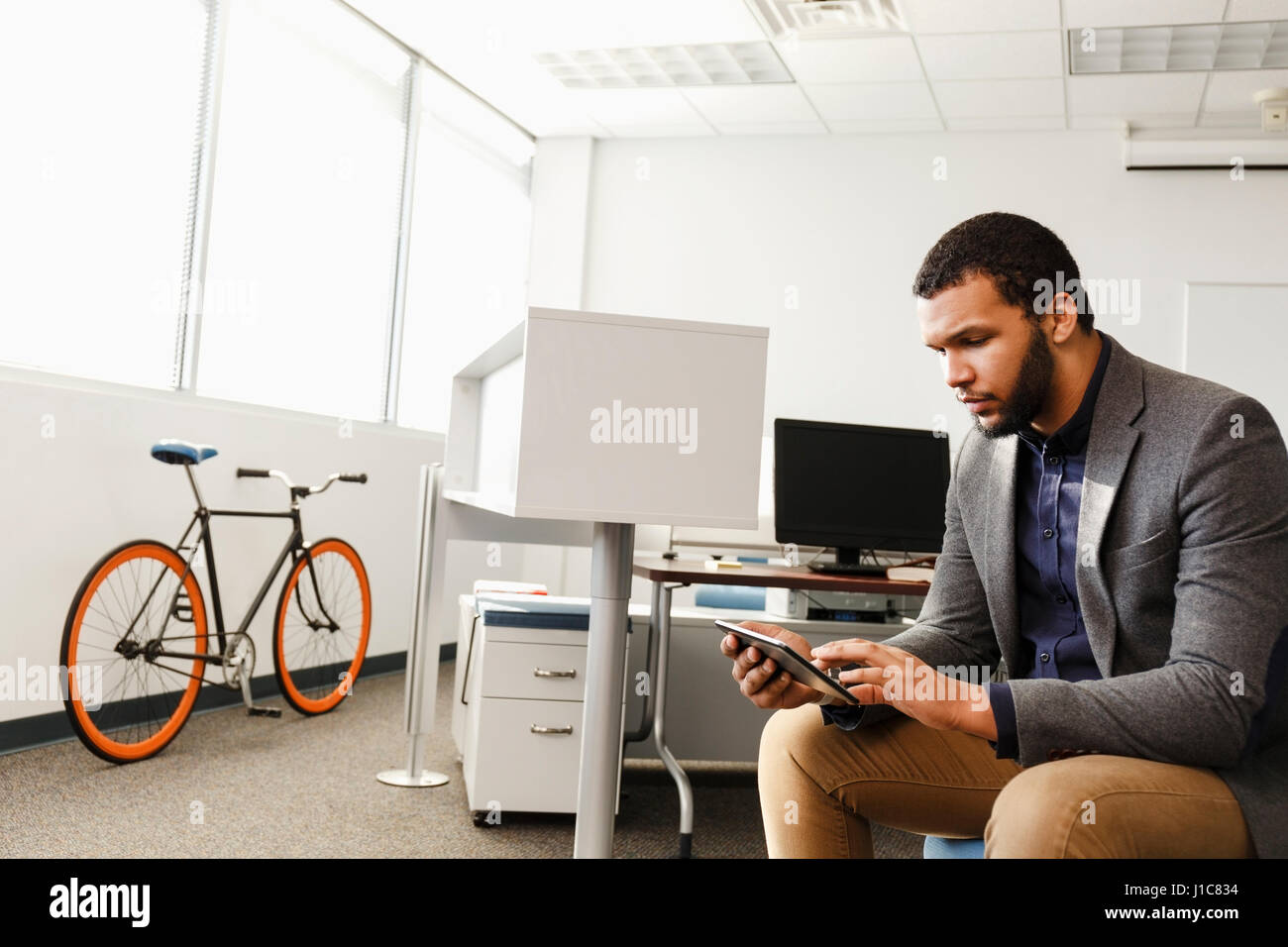 Mixed Race man using digital tablet in office Stock Photo