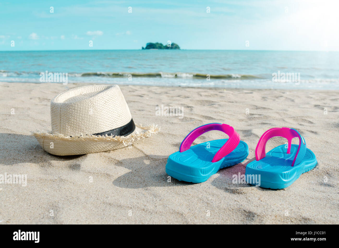 Straw hat and colorful flip flops on beach against sunny sky. Summer ...