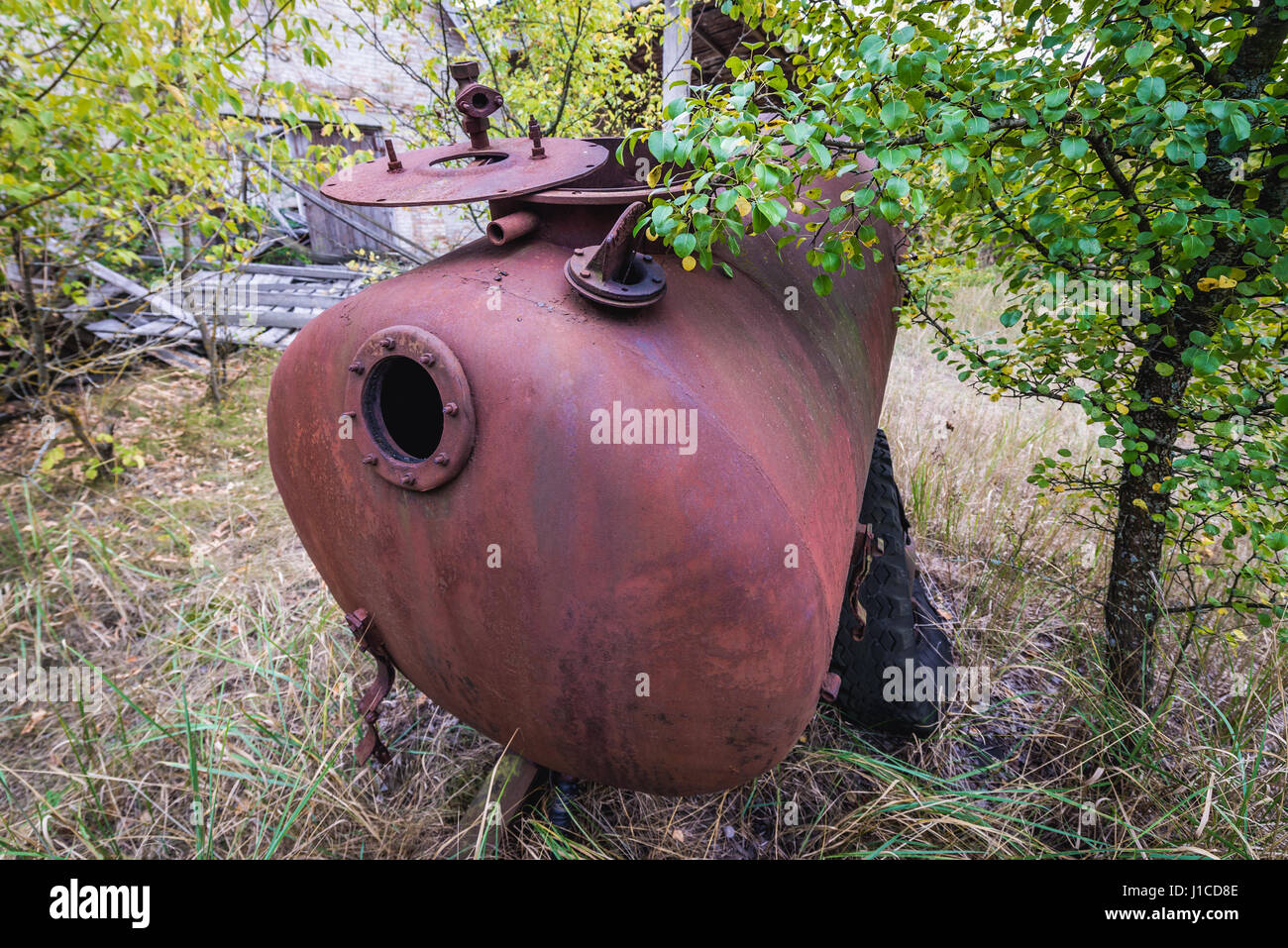 Old rusty cistern in kolkhoz near Zymovyshche village in Chernobyl Nuclear Power Plant Zone of Alienation around nuclear reactor disaster, Ukraine Stock Photo