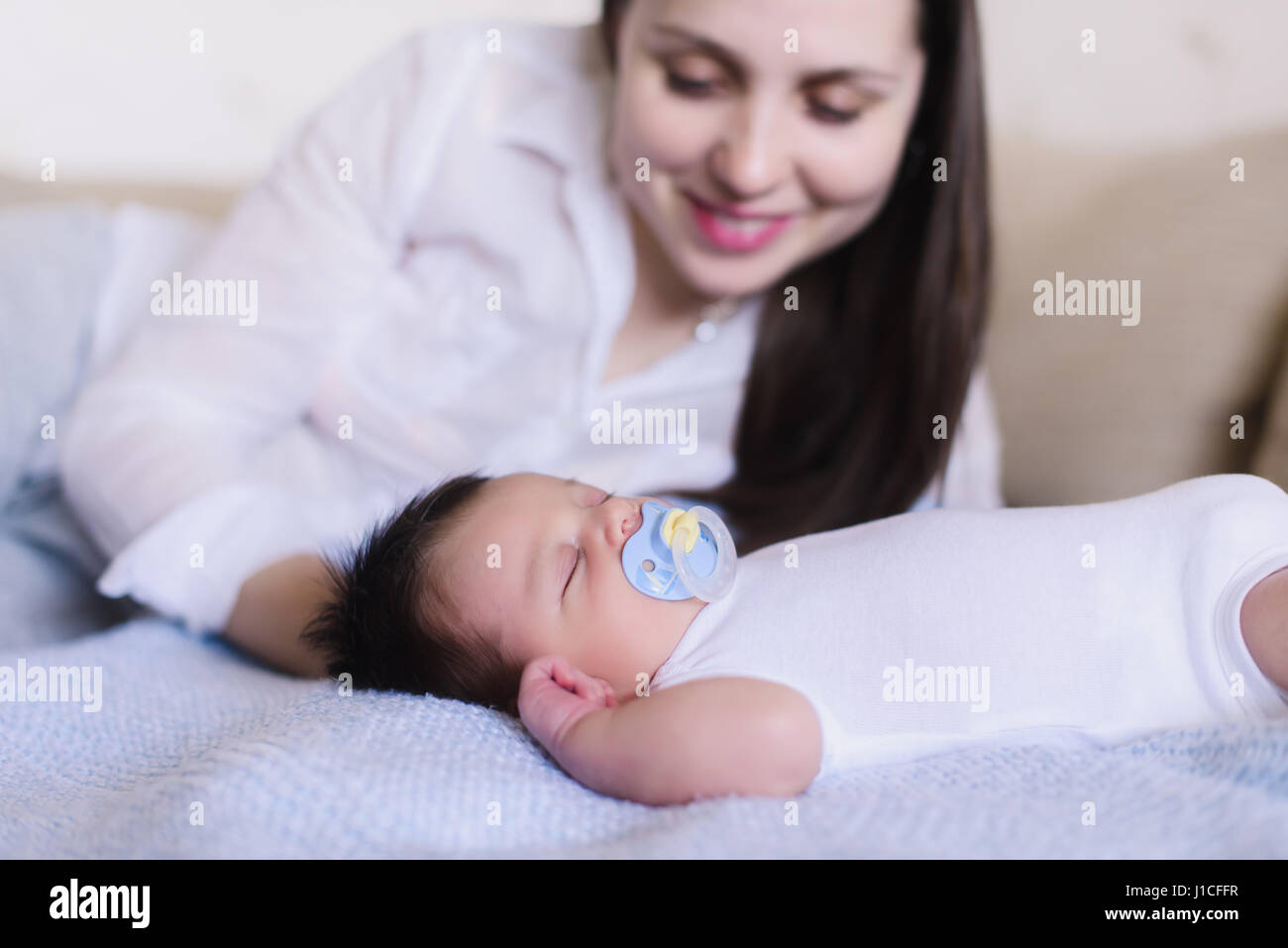 Newborn baby boy with mother. Baby sweet sleeping on a white bed. Child