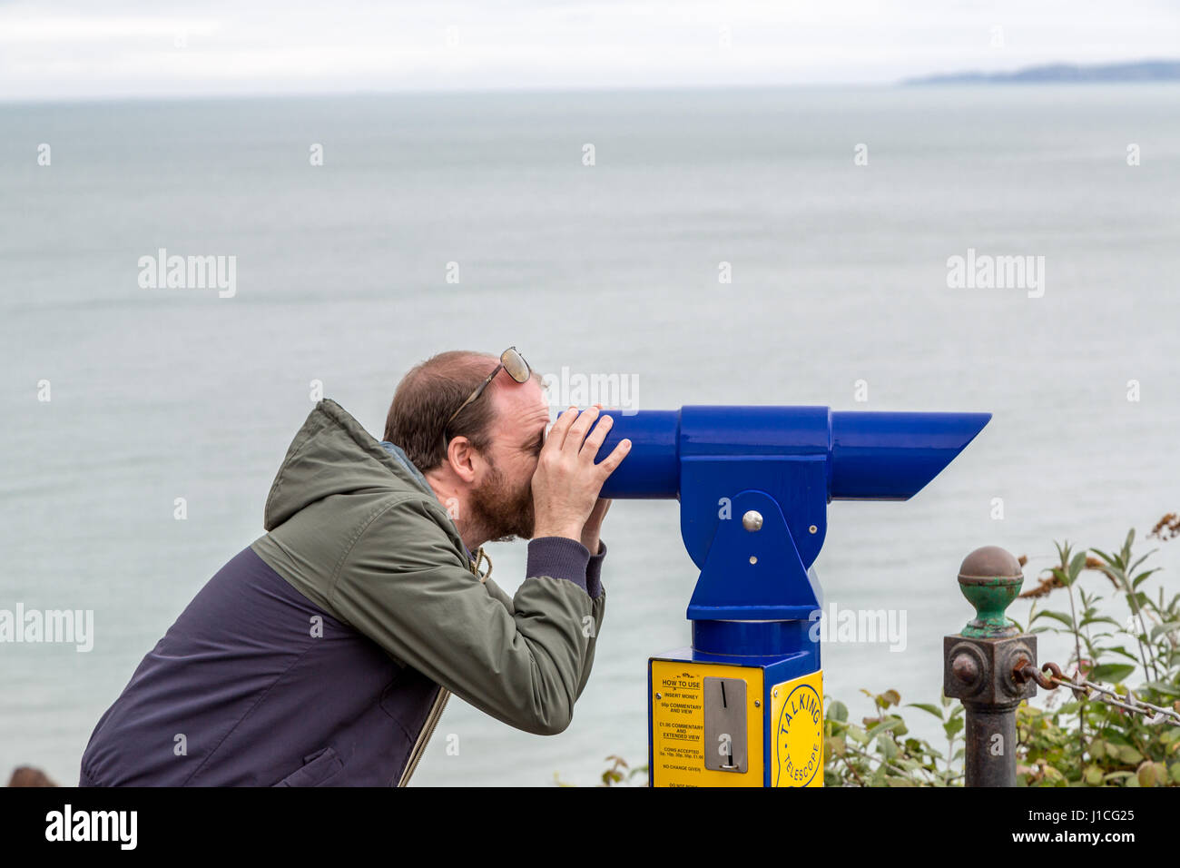 A man looking through telescope out to sea,Devon ,England,UK Stock Photo