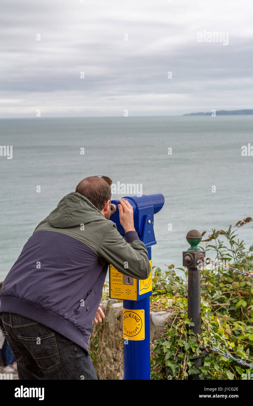 A man looking through telescope out to sea,Devon ,England,UK Stock Photo