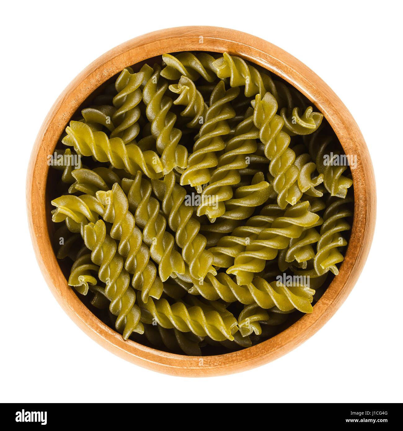Green peas fusilli pasta in wooden bowl. Uncooked dried glutenfree noodles made from Pisum sativum flour. Short length corkscrew shaped pasta. Stock Photo