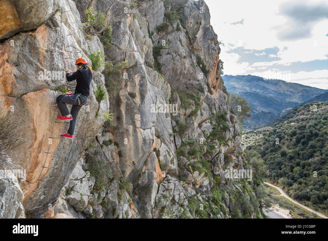 Side view of a woman on a ladder climbing up to the mountain. Horizontal outdoors shot Stock Photo