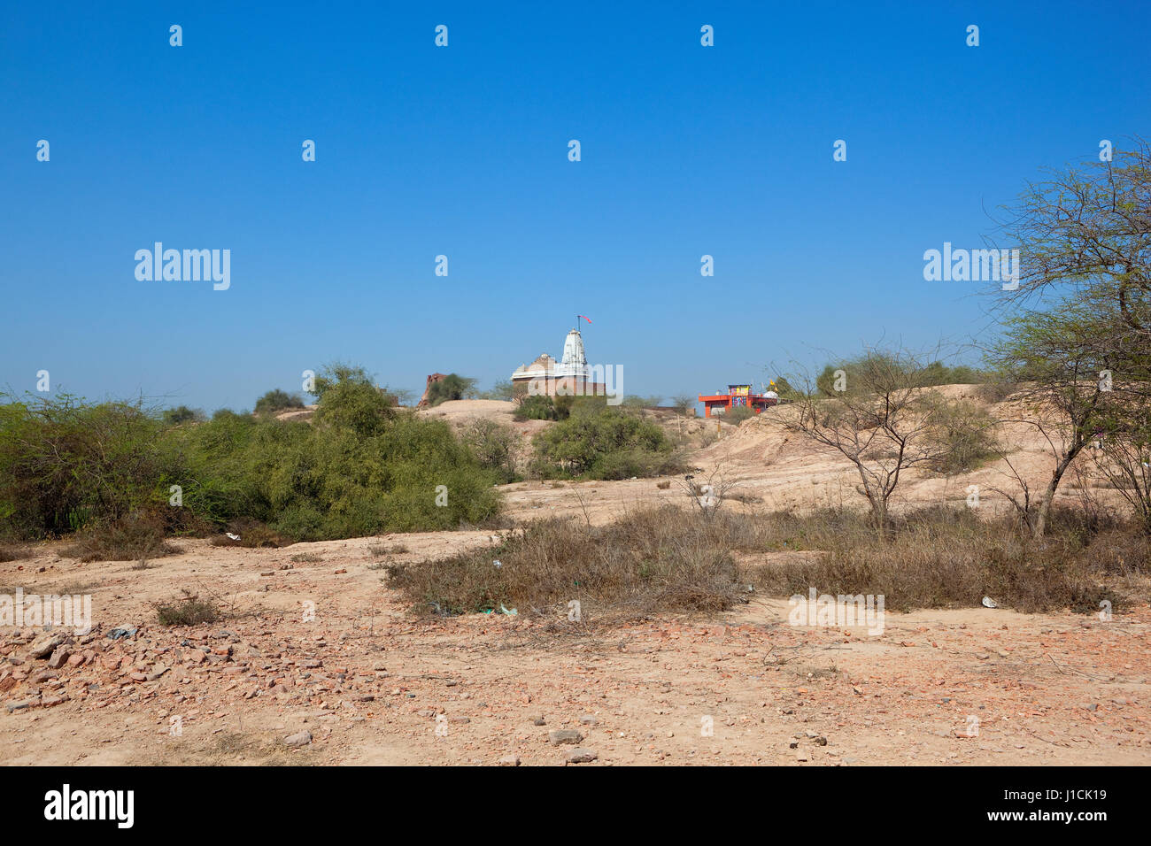 a hindu temple on top of bhatner fort hanumangarh rajasthan india surrounded by ongoing restoration work and acacia trees under a blue sky Stock Photo