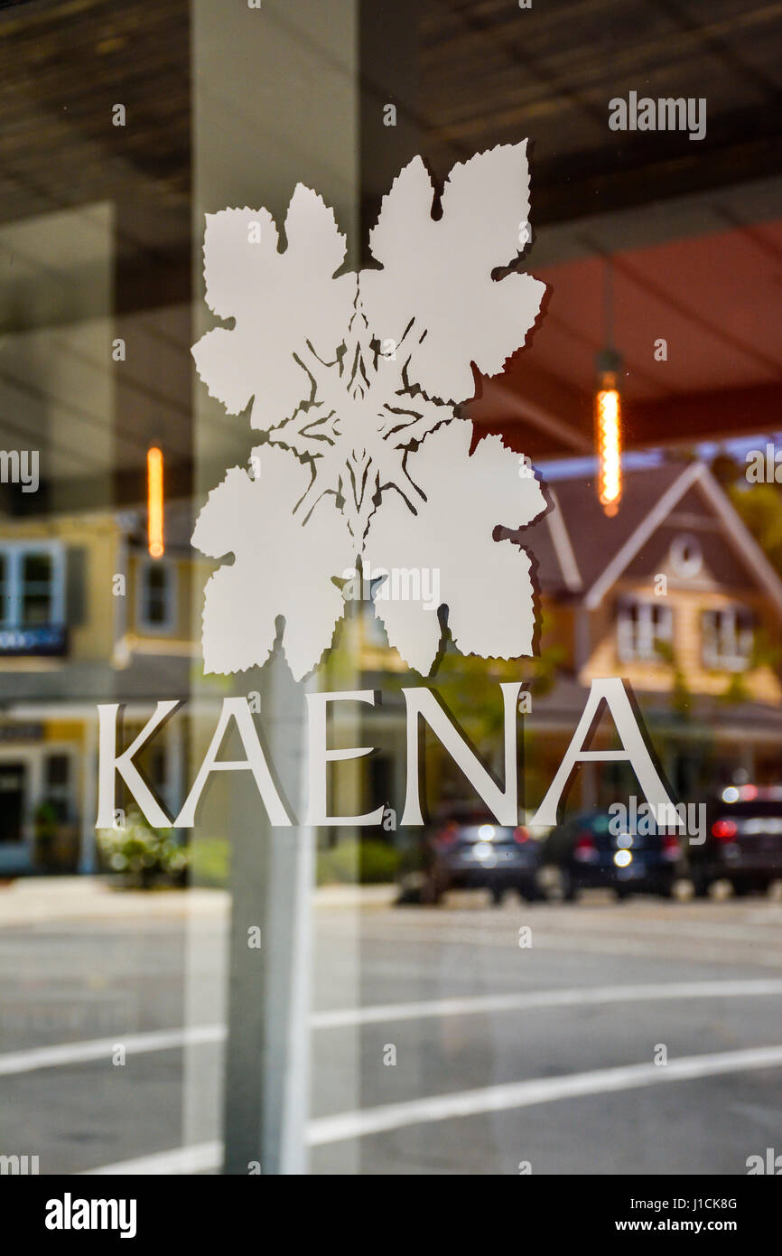 A street in the quaint town of Los Olivos, CA, reflects into the glass entrance door to Kaena Wine tasting room with their island flower motif art Stock Photo