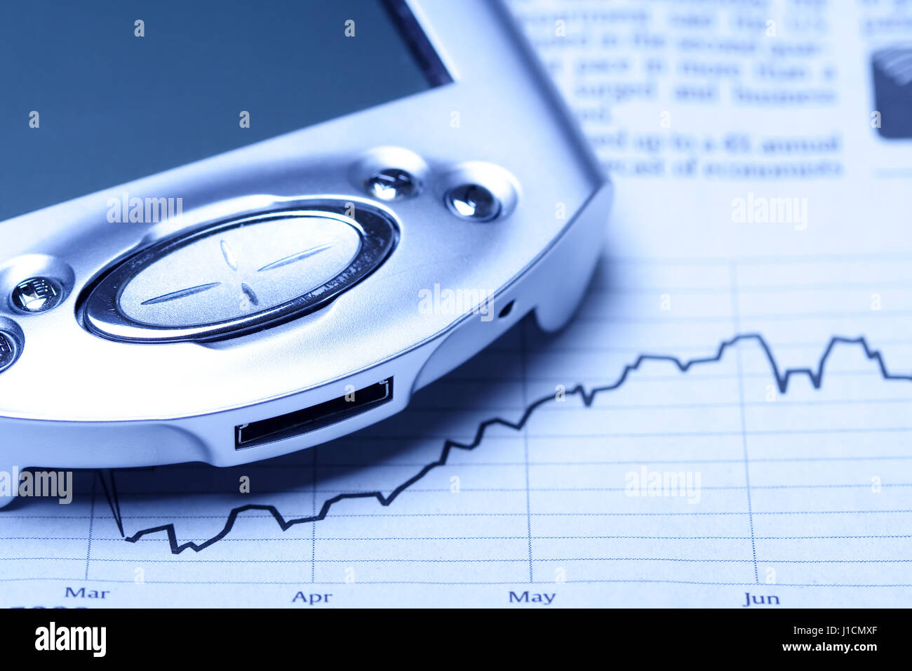 A shot of a PDA on top of financial chart in blue tone Stock Photo Alamy