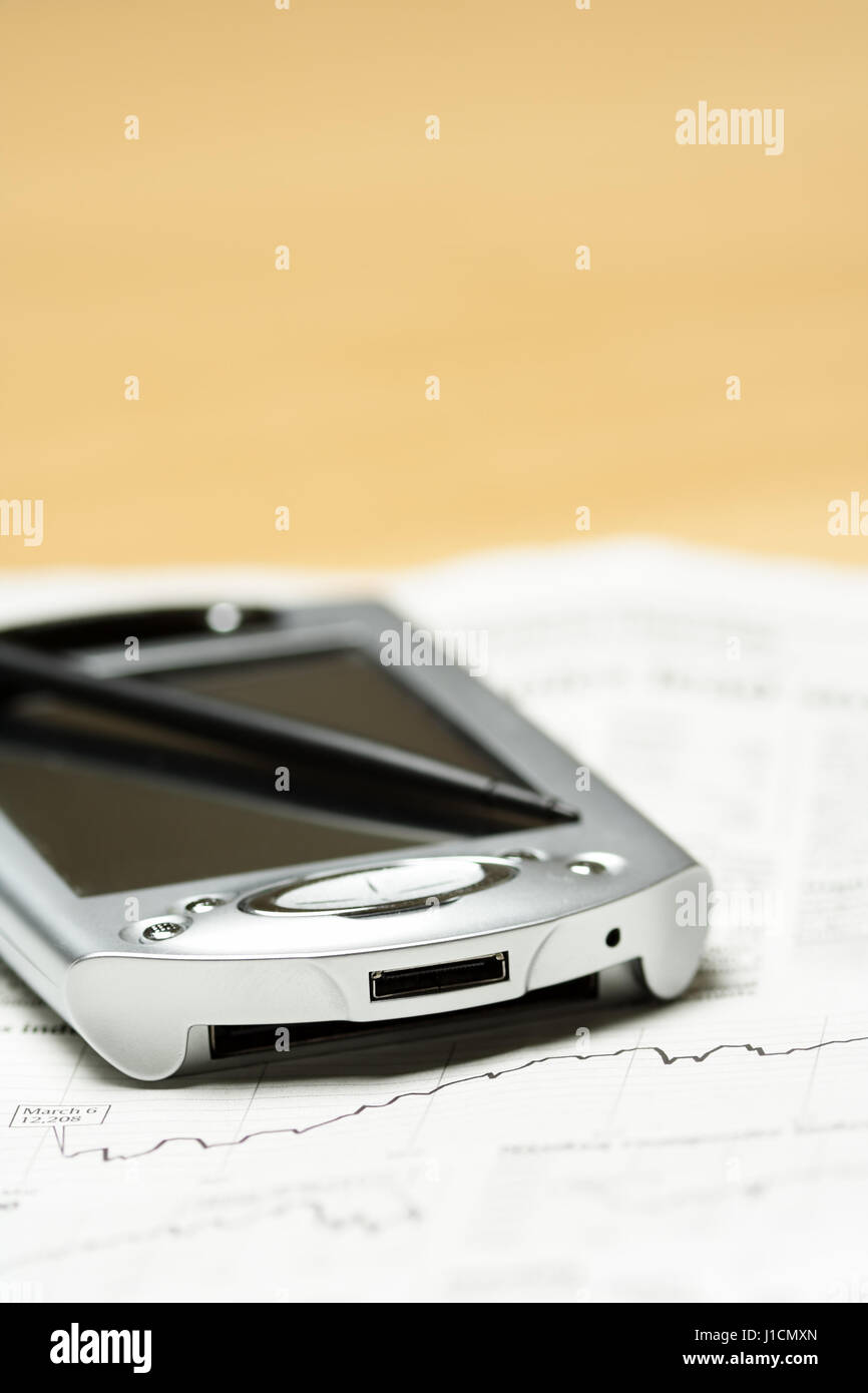 A shot of a PDA and financial chart on the newspaper Stock Photo Alamy