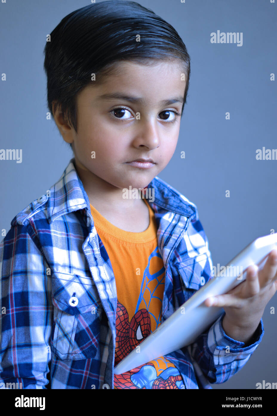 Smart Kid holding a tablet computer looking towards the camera lens Stock  Photo - Alamy