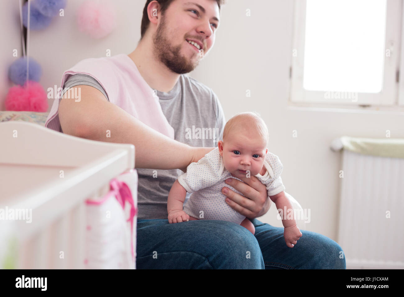 Young father burping his newborn daughter, holding her affectionately. Lifestyle family session.. Stock Photo