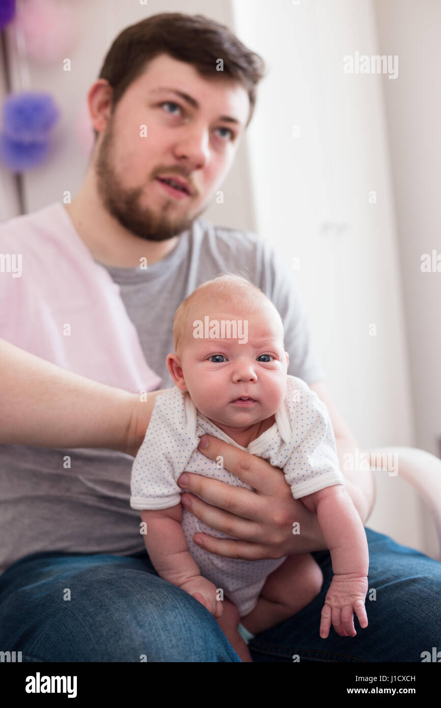 Young father burping his newborn daughter, holding her affectionately. Lifestyle family session.. Stock Photo