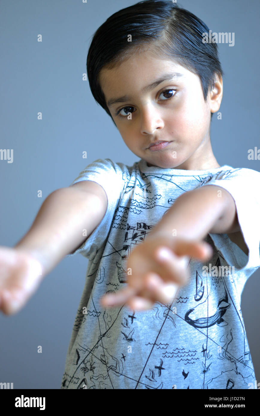 Grumpy kid with both arms asking for help. Sad Kid with arms stretched out. Unhappy child Stock Photo