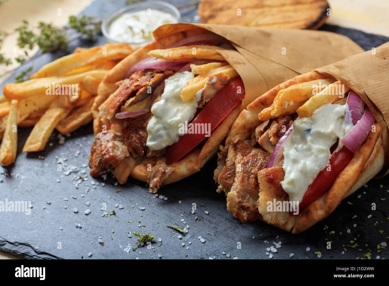 Greek gyros wrapped in pita breads on a black plate Stock Photo ...