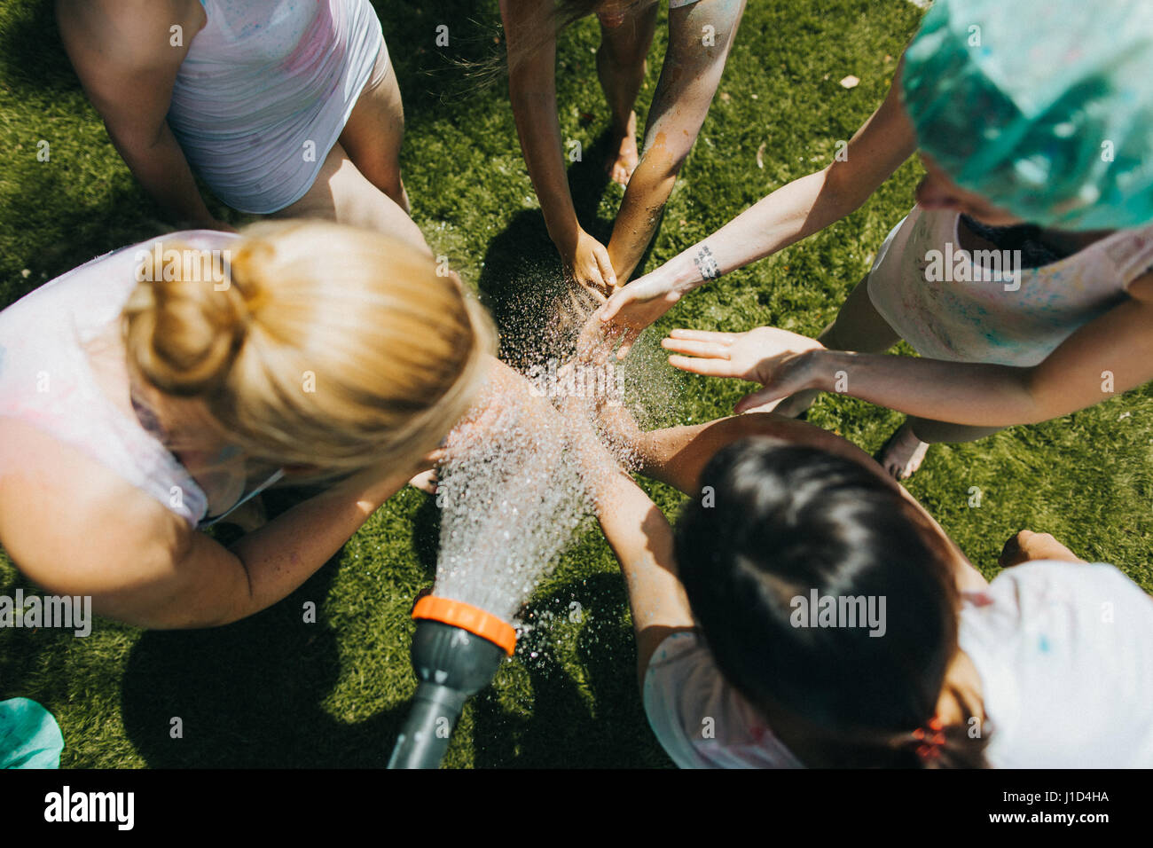 young women washing their hands in the garden on a hot summers day Stock Photo