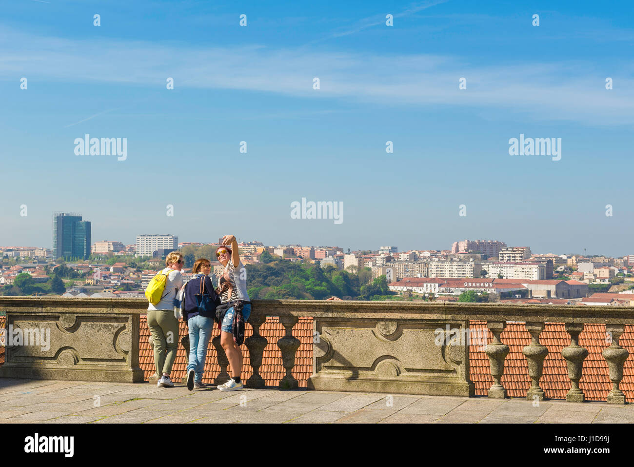 Women tourists, view of three young women tourists posing for a selfie on the terrace of the Cathedral, or Se, above the old town district in Porto. Stock Photo