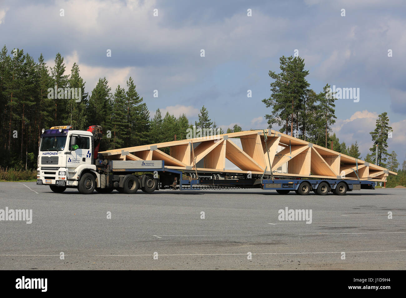 ORIVESI, FINLAND - SEPTEMBER 1, 2016: White MAN TGA 26.430 semi truck transports roof truss on flat trailer. Stock Photo