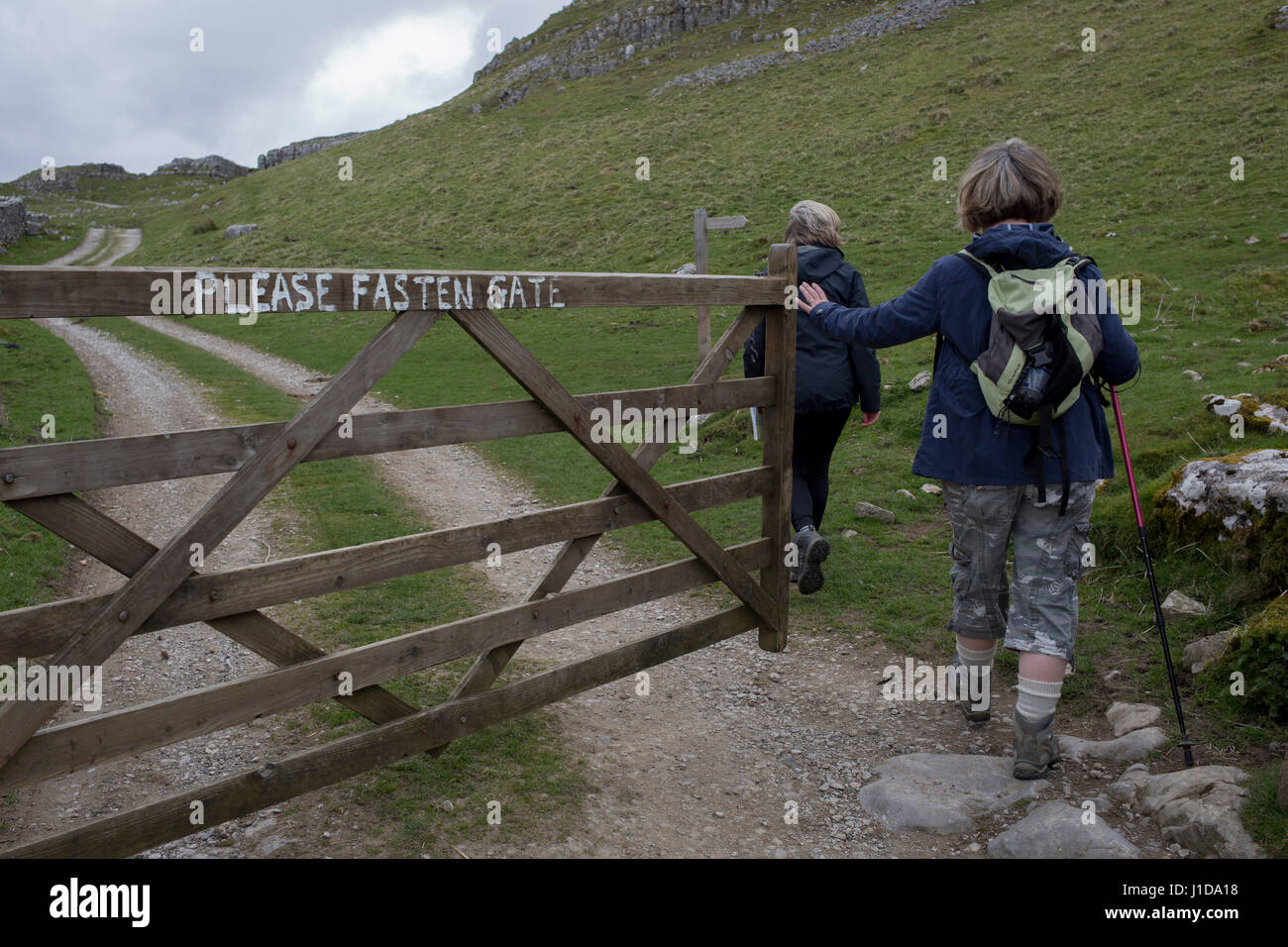 Walkers open a farmer's gate and enter a field while keeping to a