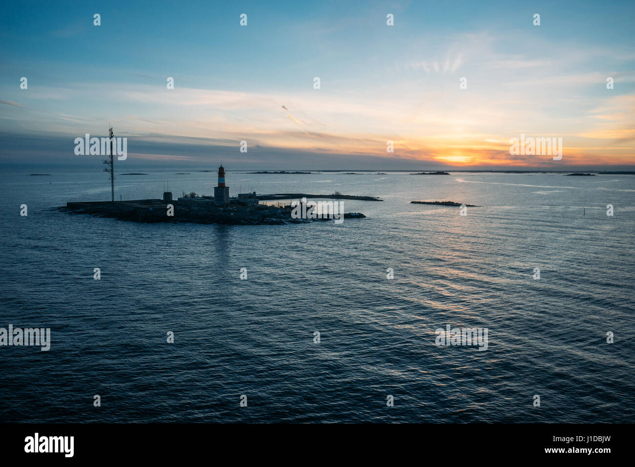 Small island with lighthouse and communication tower against scenic sunset Stock Photo