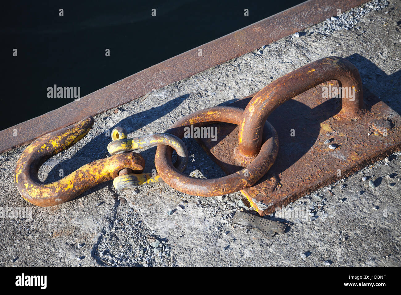 Ships mooring equipment, rusted hook mounted in concrete pier Stock Photo