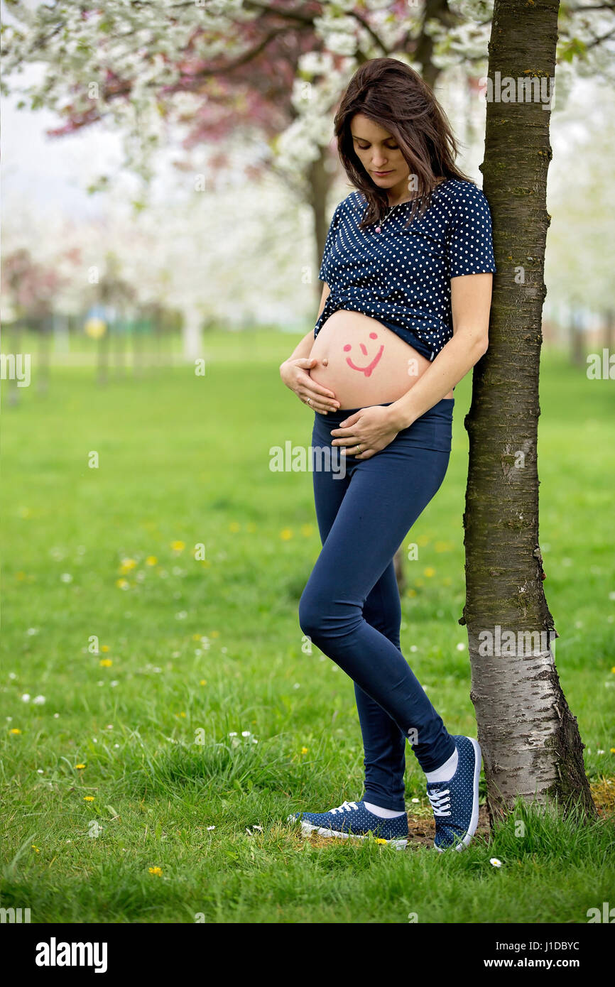 Pregnant woman in a spring blooming park, family happiness Stock Photo ...