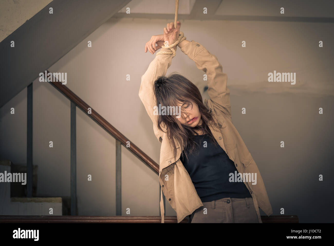 Female Hostage are tied up with ropes hanging on abandoned building ladders, Vintage tone Stock Photo