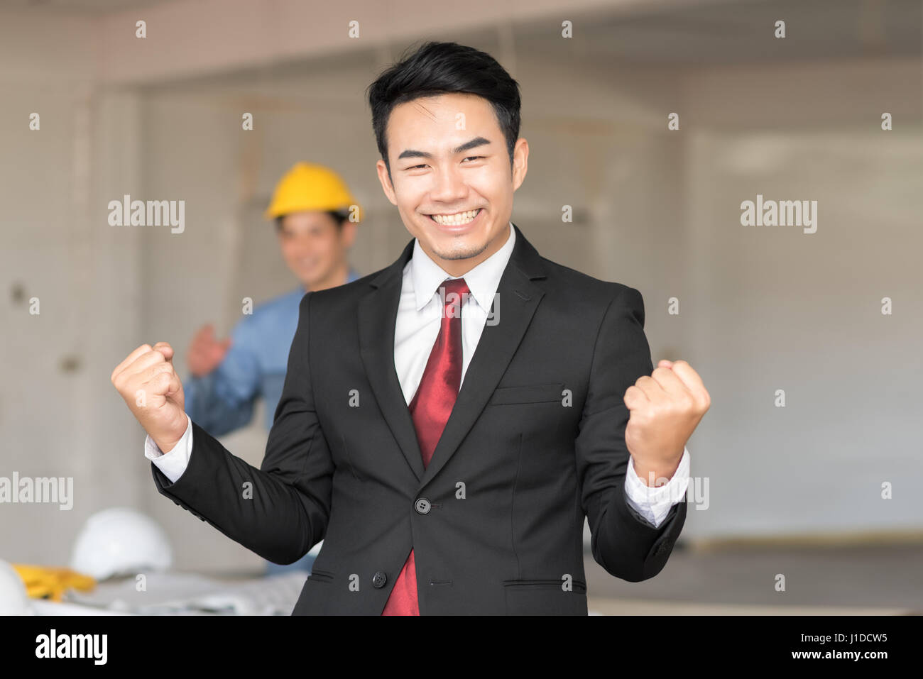 Celebrating success with excited young businessman keeping arms raised ...