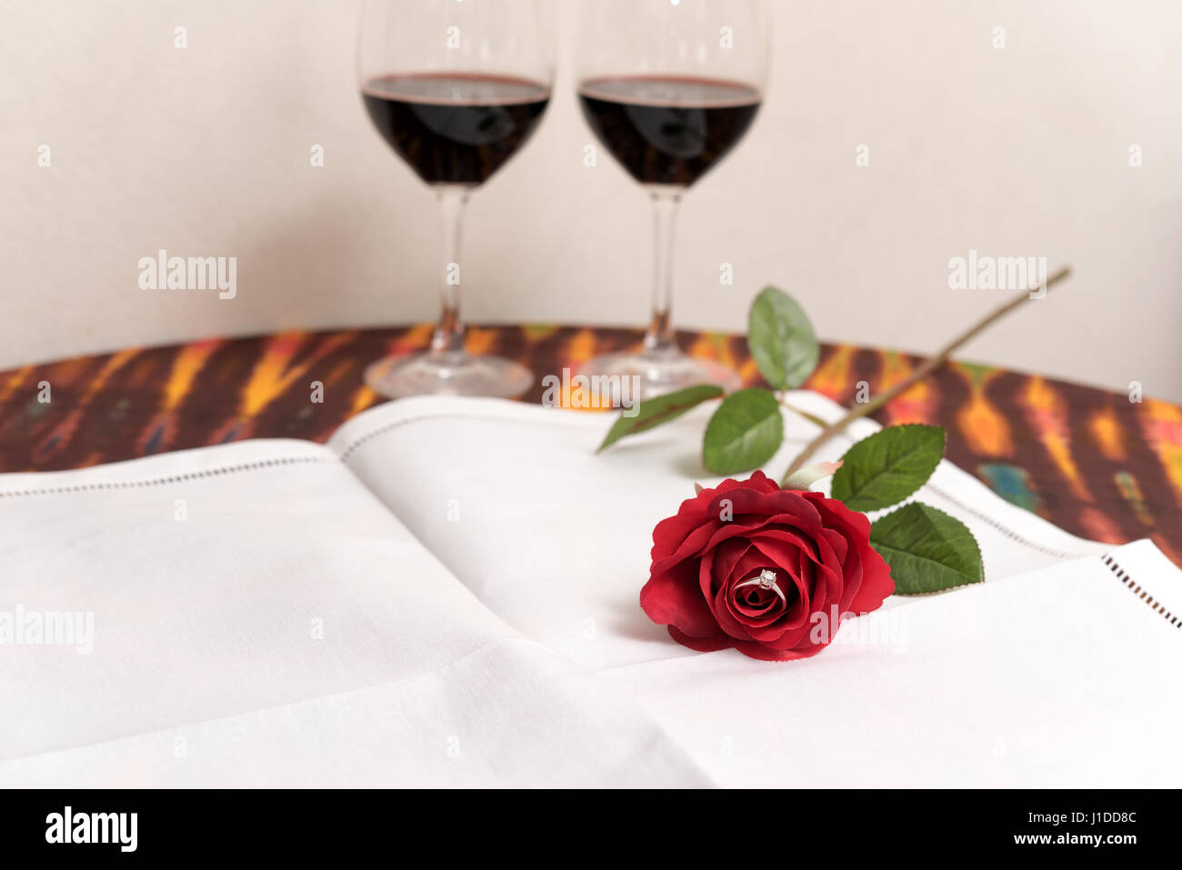 Marriage proposal concept with Diamond ring inside red rose over two wine  glasses background with copy space Stock Photo - Alamy