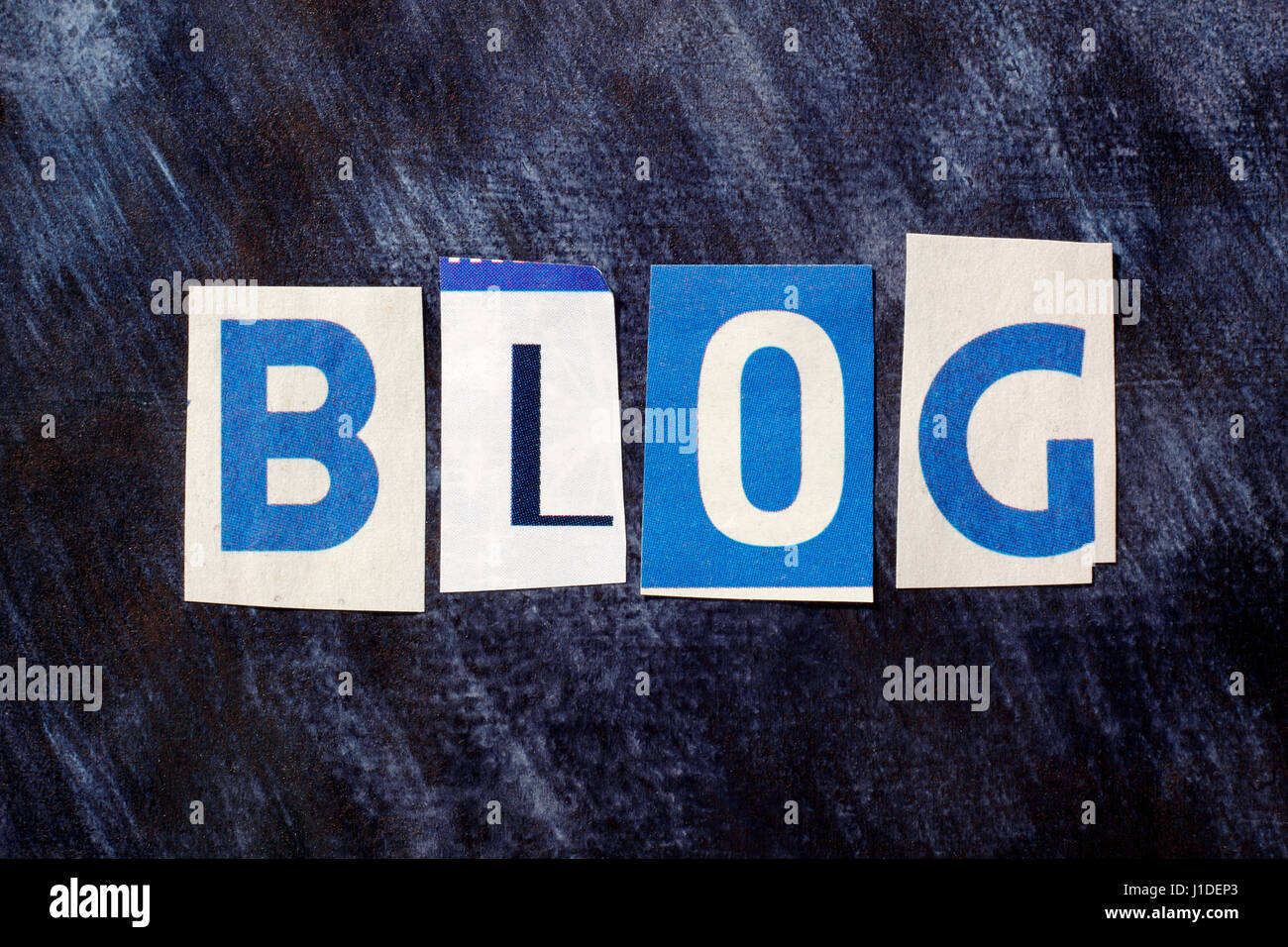 The word Blog from cut out magazine letters glued to a dark painted background Stock Photo