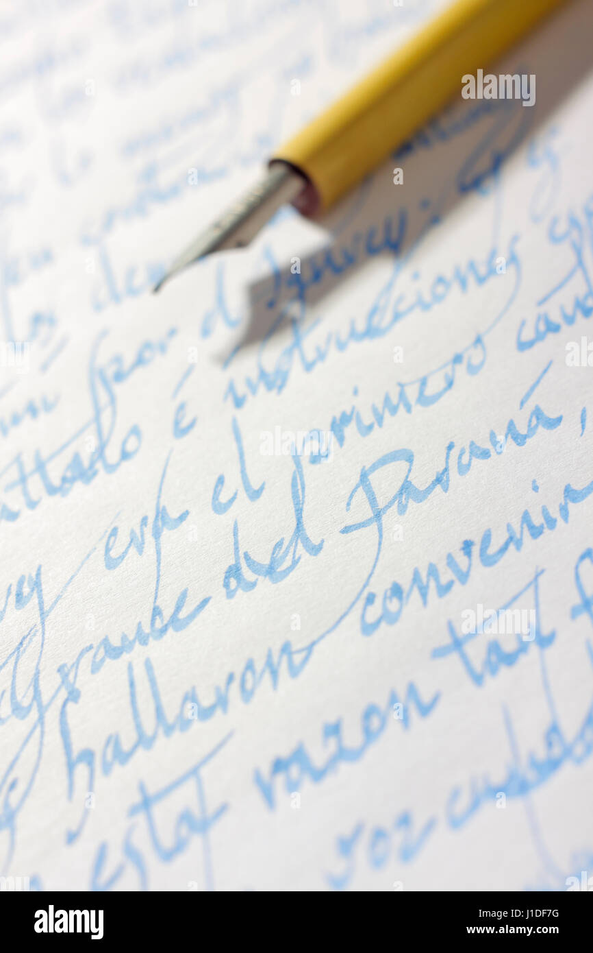 Handwritten correspondence in Spanish language (italics typeface) on paper with blue ink and ancient nib pen on background Stock Photo