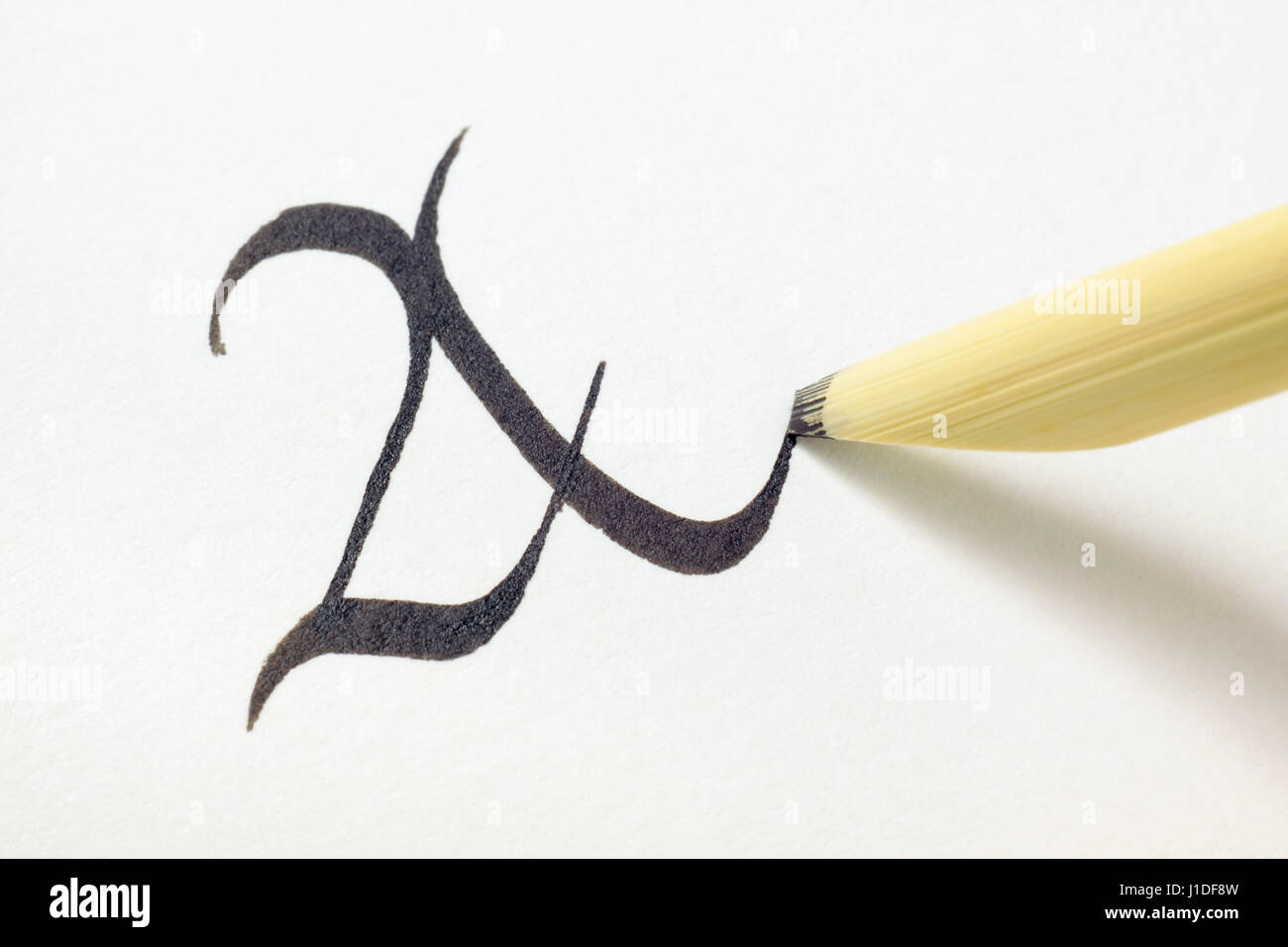 Reed pen (calamus, qalam) tip writing capital letter A in blackletter style on white paper with black ink Stock Photo