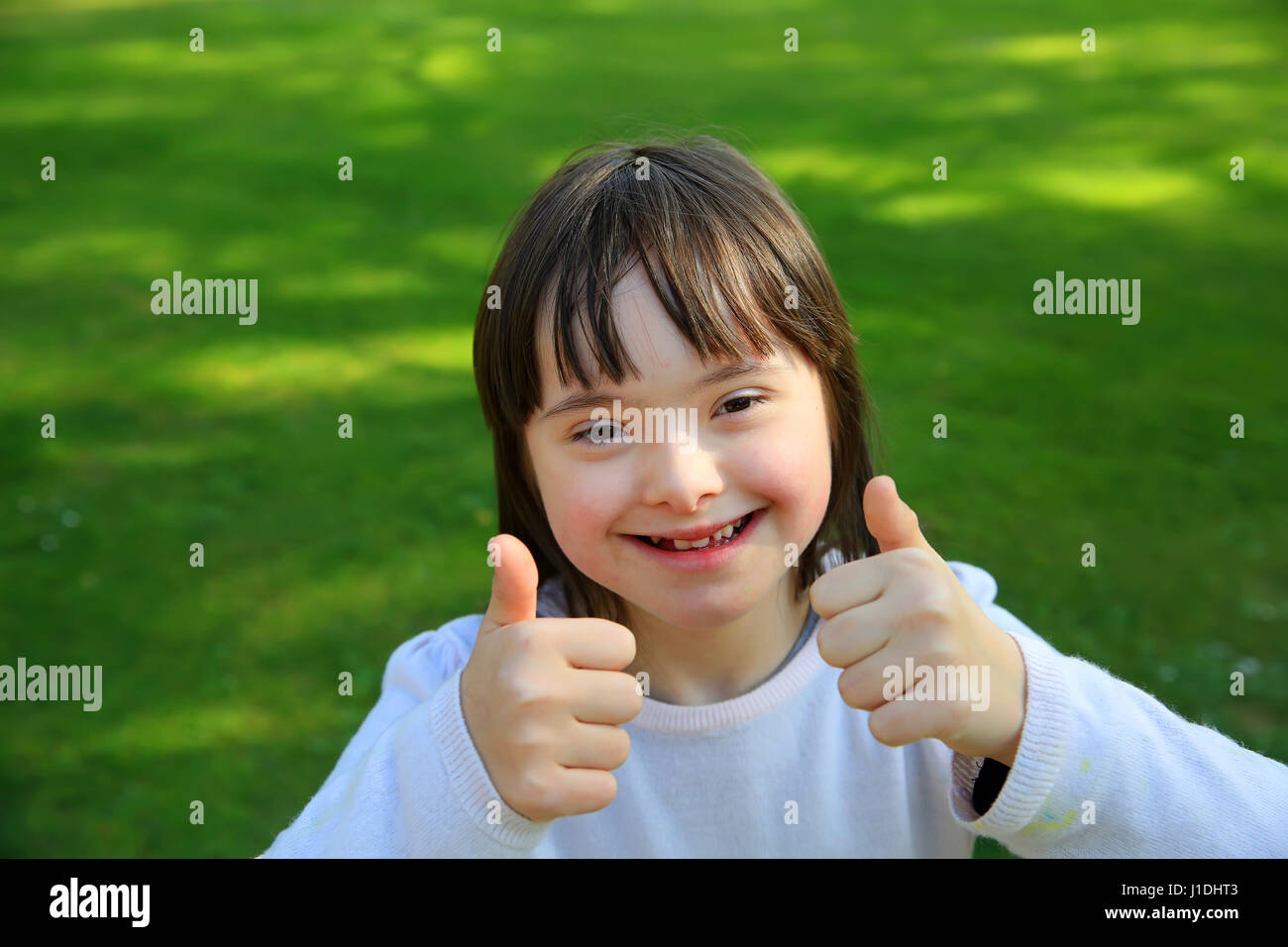 Down syndrome girl smiling in the park Stock Photo