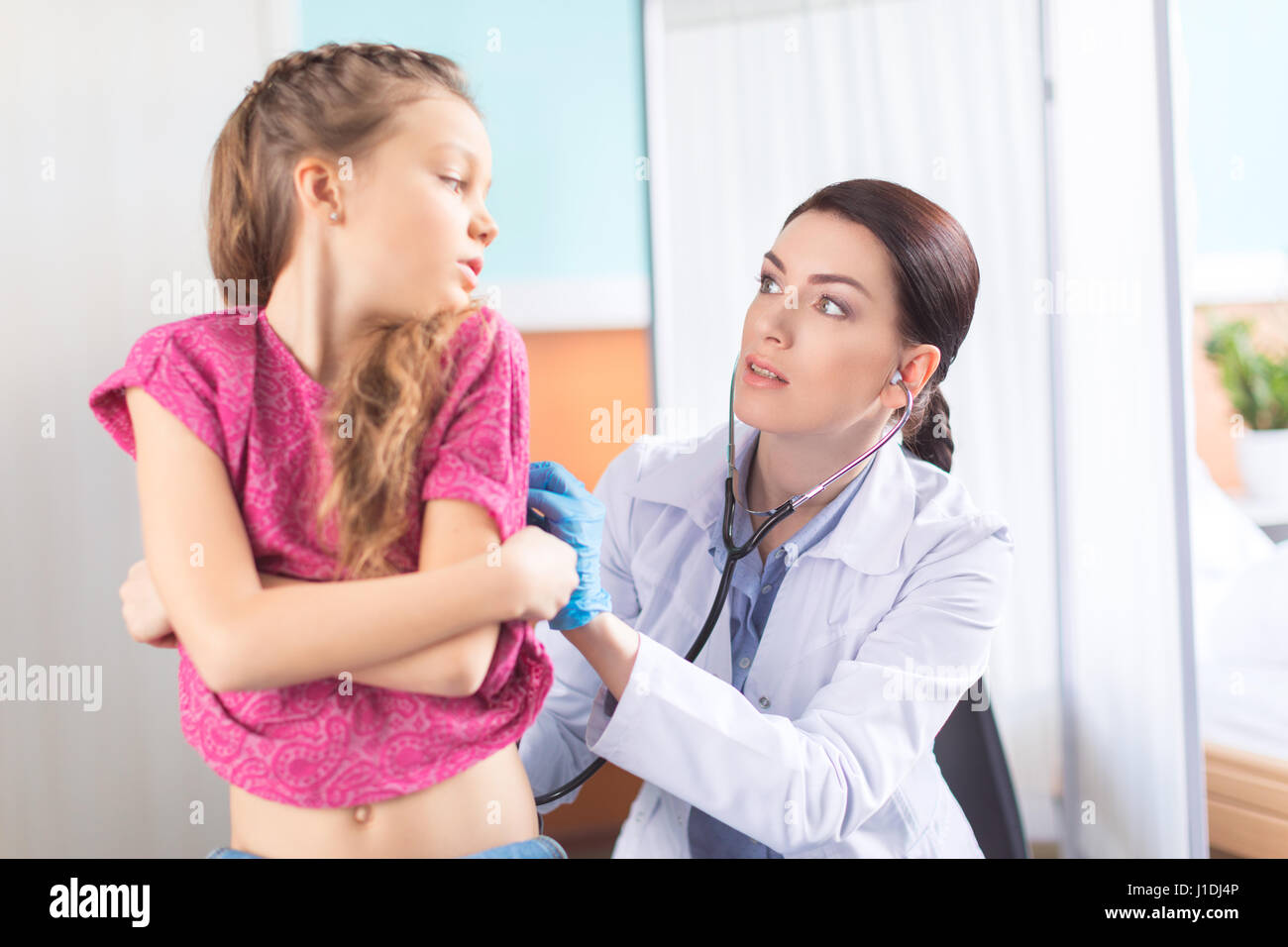 Young woman doctor with stethoscope listening to heartbeat and lungs of  little girl patient Stock Photo - Alamy