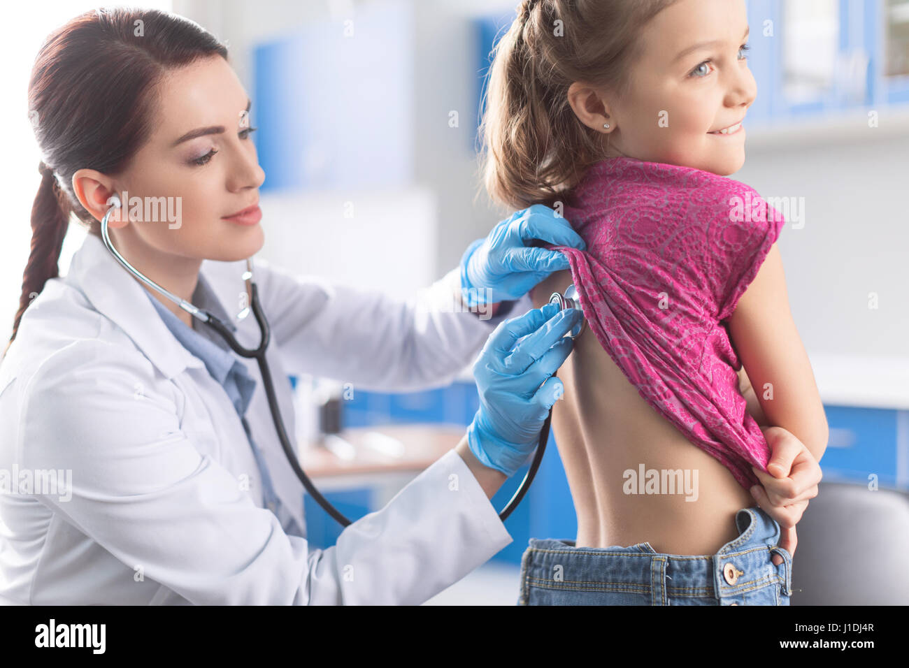 Young woman doctor with stethoscope listening to heartbeat and lungs of ...