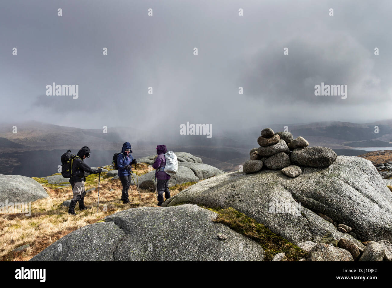 Walkers on the Summit of Criagnaw Bracing Themselves Against the Wind as a Heavy Snow Squall Hits Them, Galloway Hills, Scotland Stock Photo