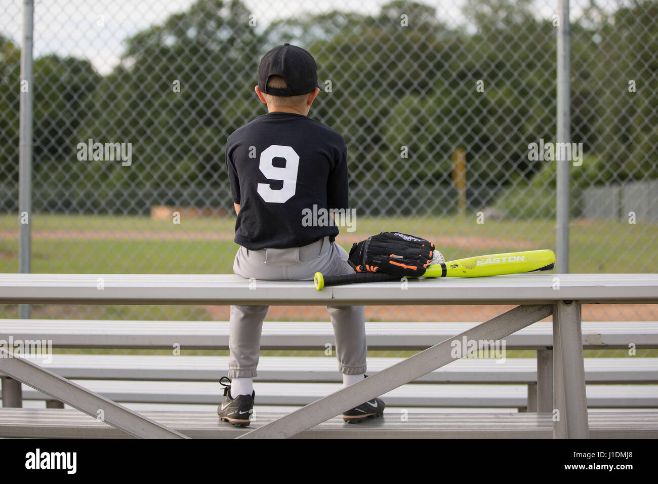 8 year old boy in baseball uniform at baseball field with baseball bat and mitt Stock Photo