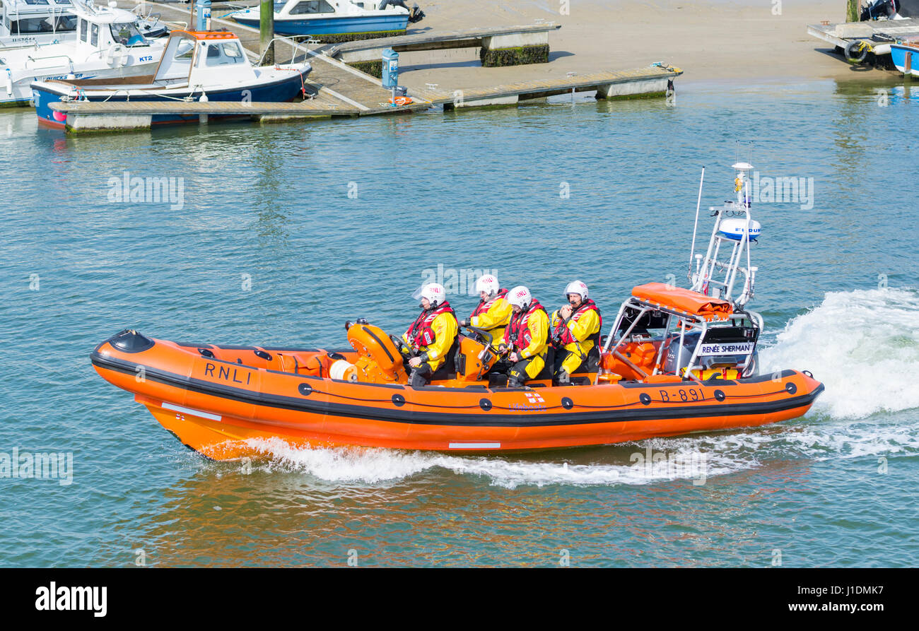 RNLI crew speeding up a river estuary in an inshore lifeboat rib on the River Arun, Littlehampton, West Sussex, England, UK. Stock Photo