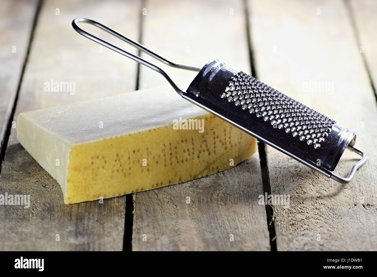 Italian hard cheese with grater on wooden background Stock Photo