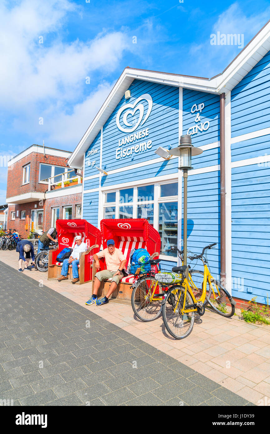 SYLT ISLAND, GERMANY - SEP 6, 2016: people relaxing in beach chairs in front of typical blue building with shops inside in List port on northern coast Stock Photo
