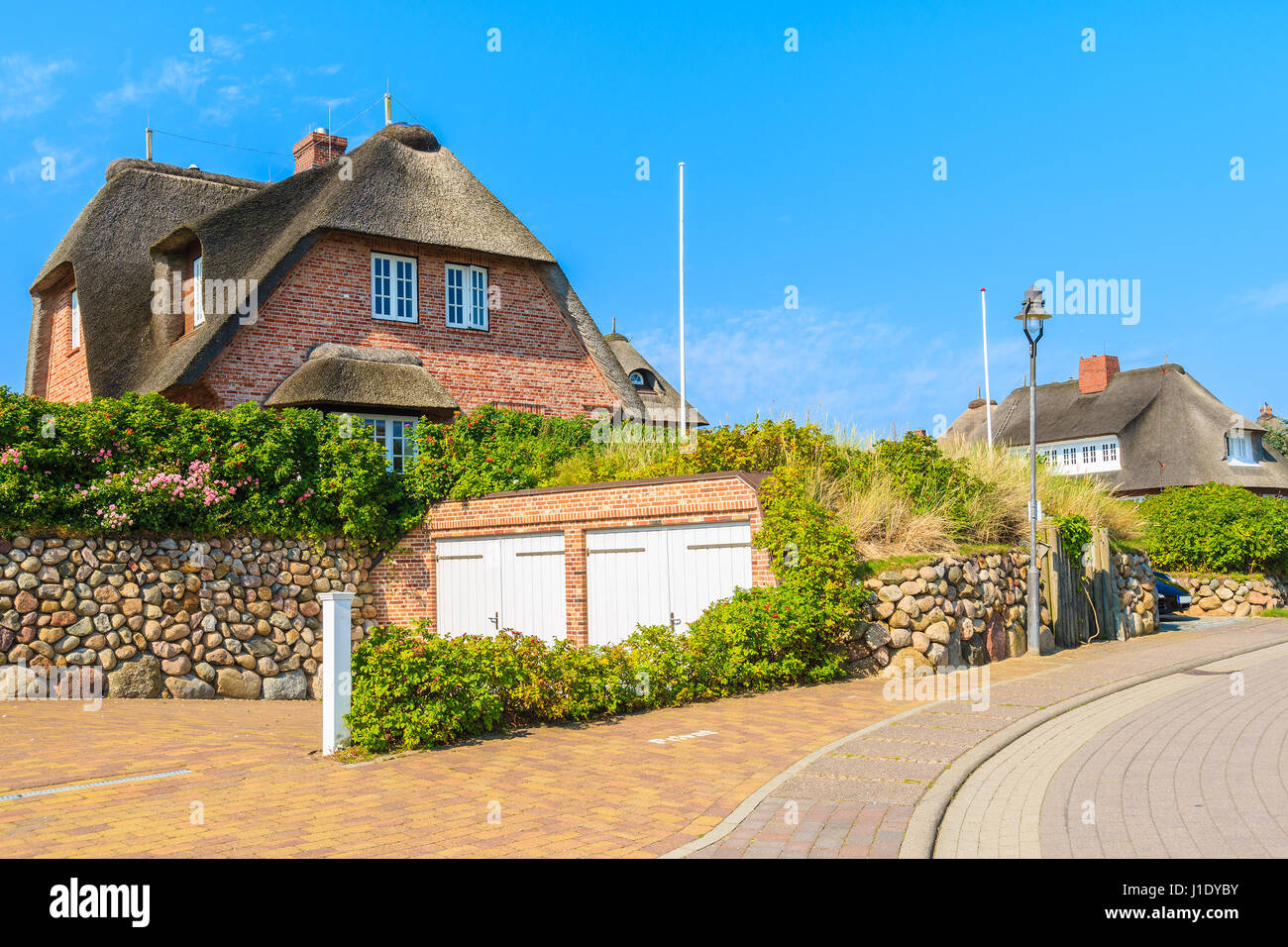 Stree and typical red brick houses with straw roofs in Rantum village, Sylt island, Germany Stock Photo